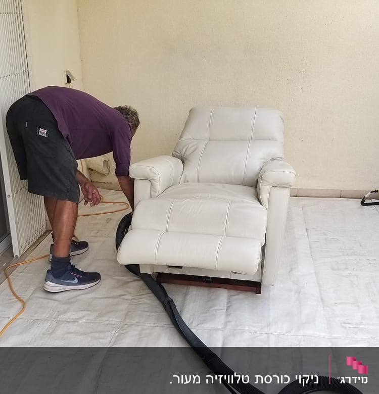 אדם מנקה כורסה עם שואב אבק ודלי מים